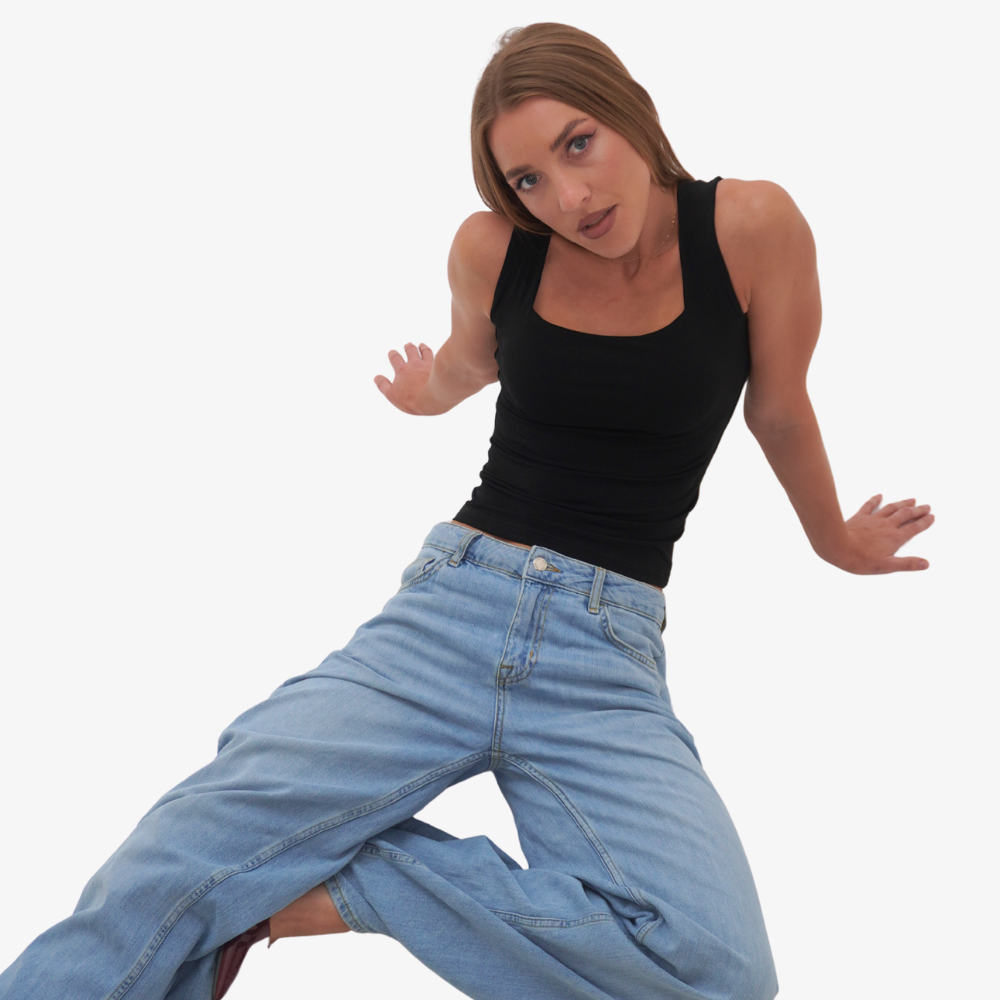 Charlotte top Woman wearing a black tank top and blue jeans on a white background