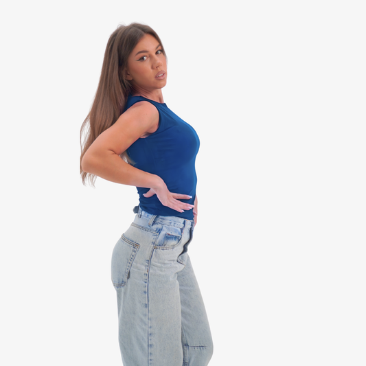 Emma - straight neckline top Woman wearing a blue sleeveless top and light blue jeans on a white background