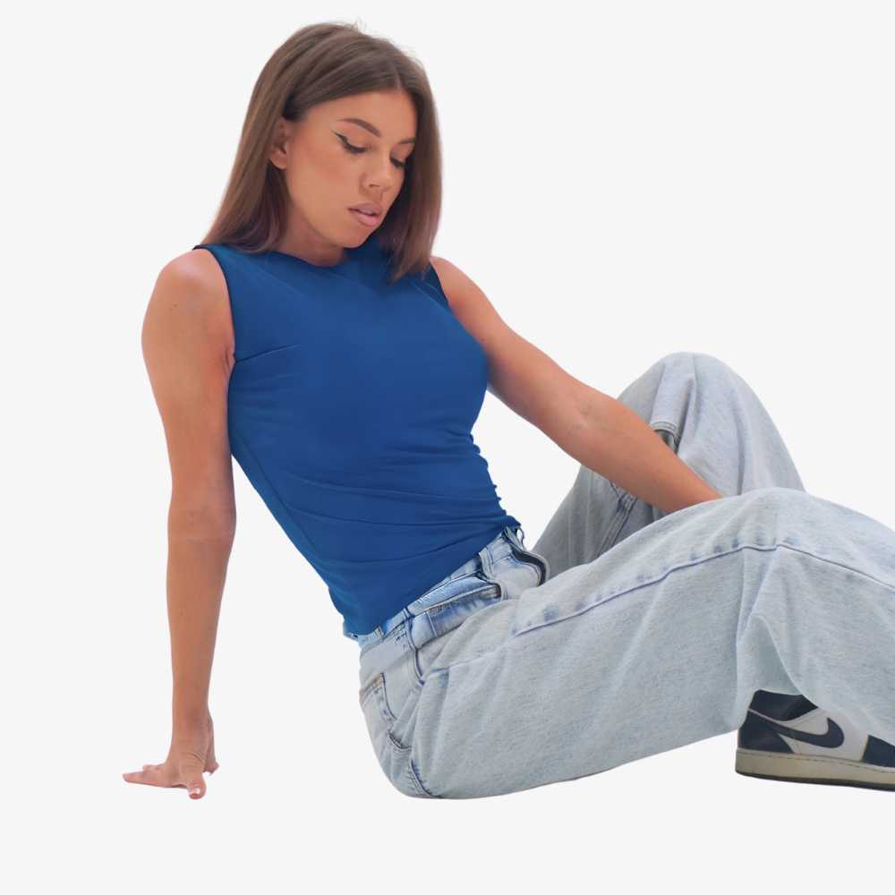 Emma - straight neckline top Woman sitting on the floor wearing a blue sleeveless top and light blue jeans.