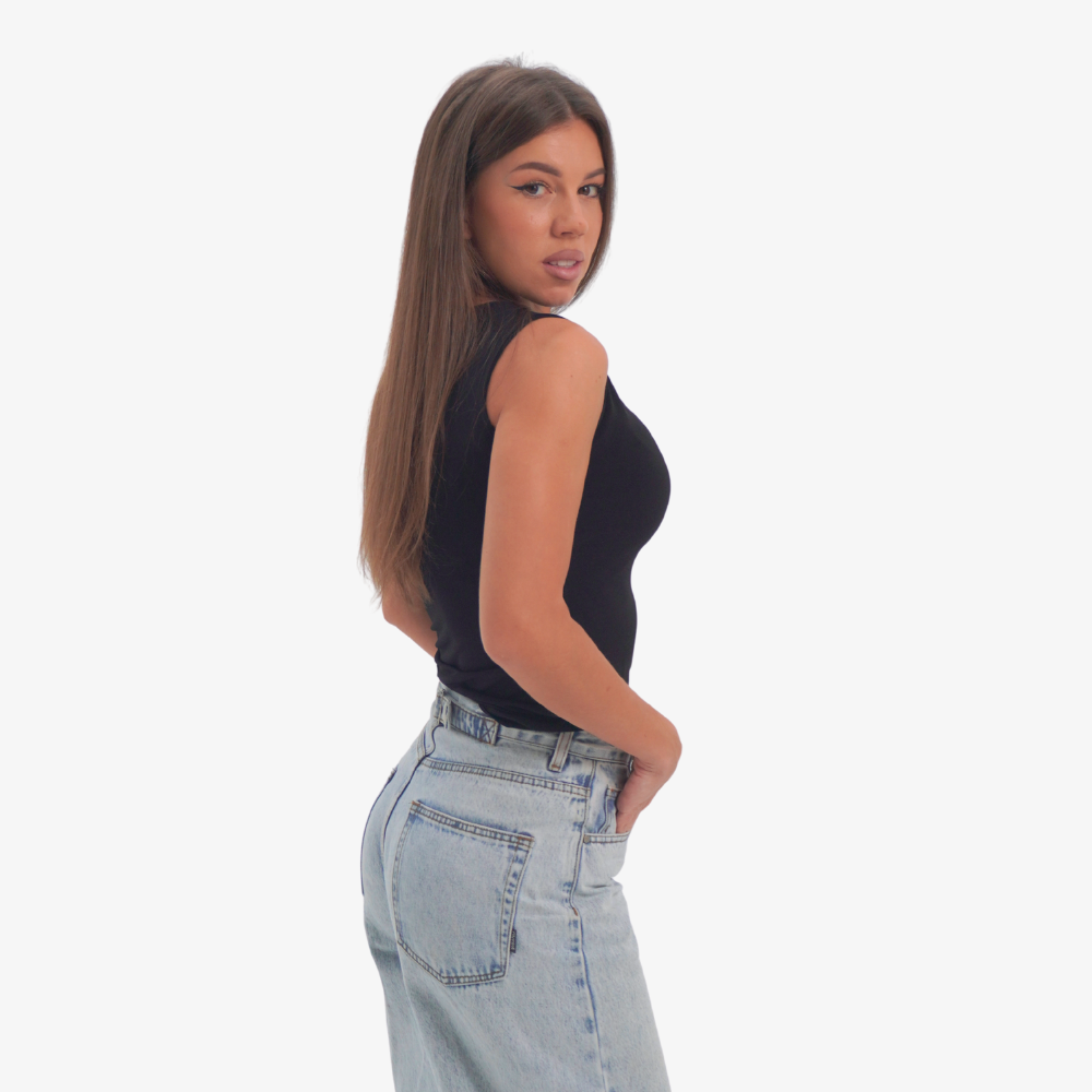 Emma - straight neckline top Woman wearing a black sleeveless top and light blue jeans on a white background