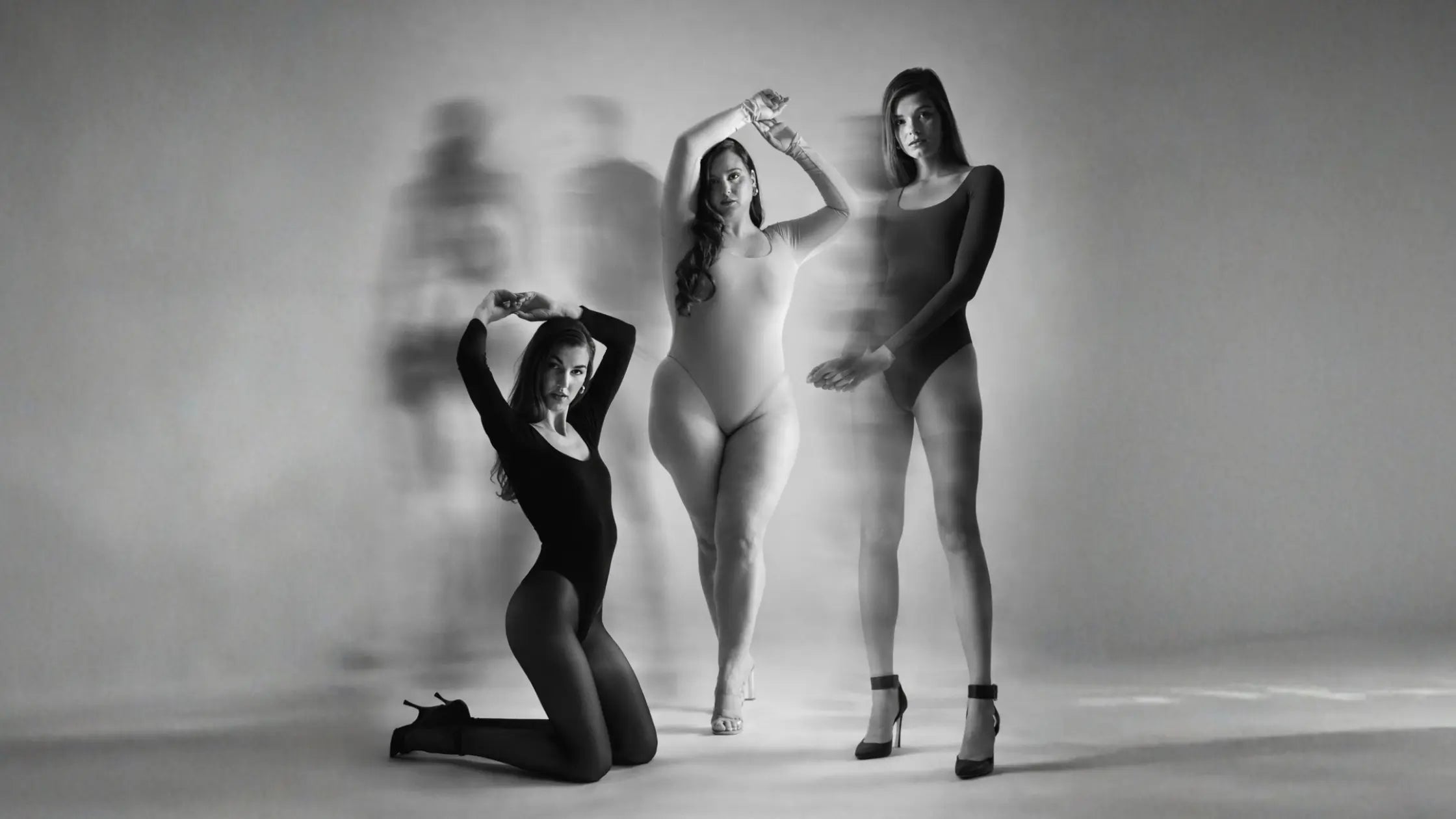 Three women of different body types posing together in a black and white photo. wearing tcheriz bodysuit