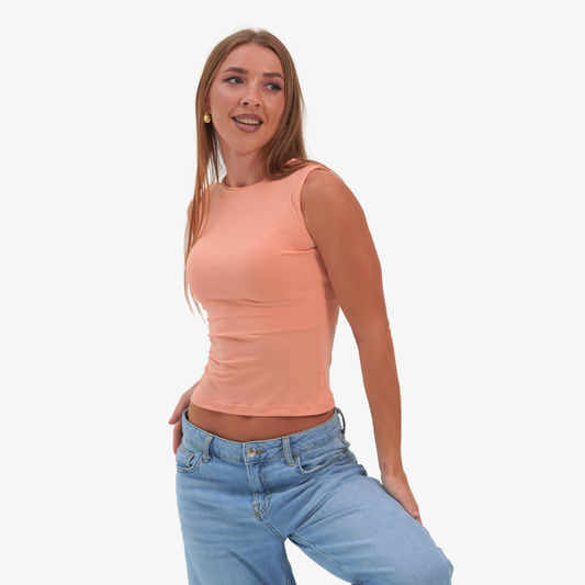 Emma - straight neckline top Woman wearing a peach sleeveless top and blue jeans on a white background