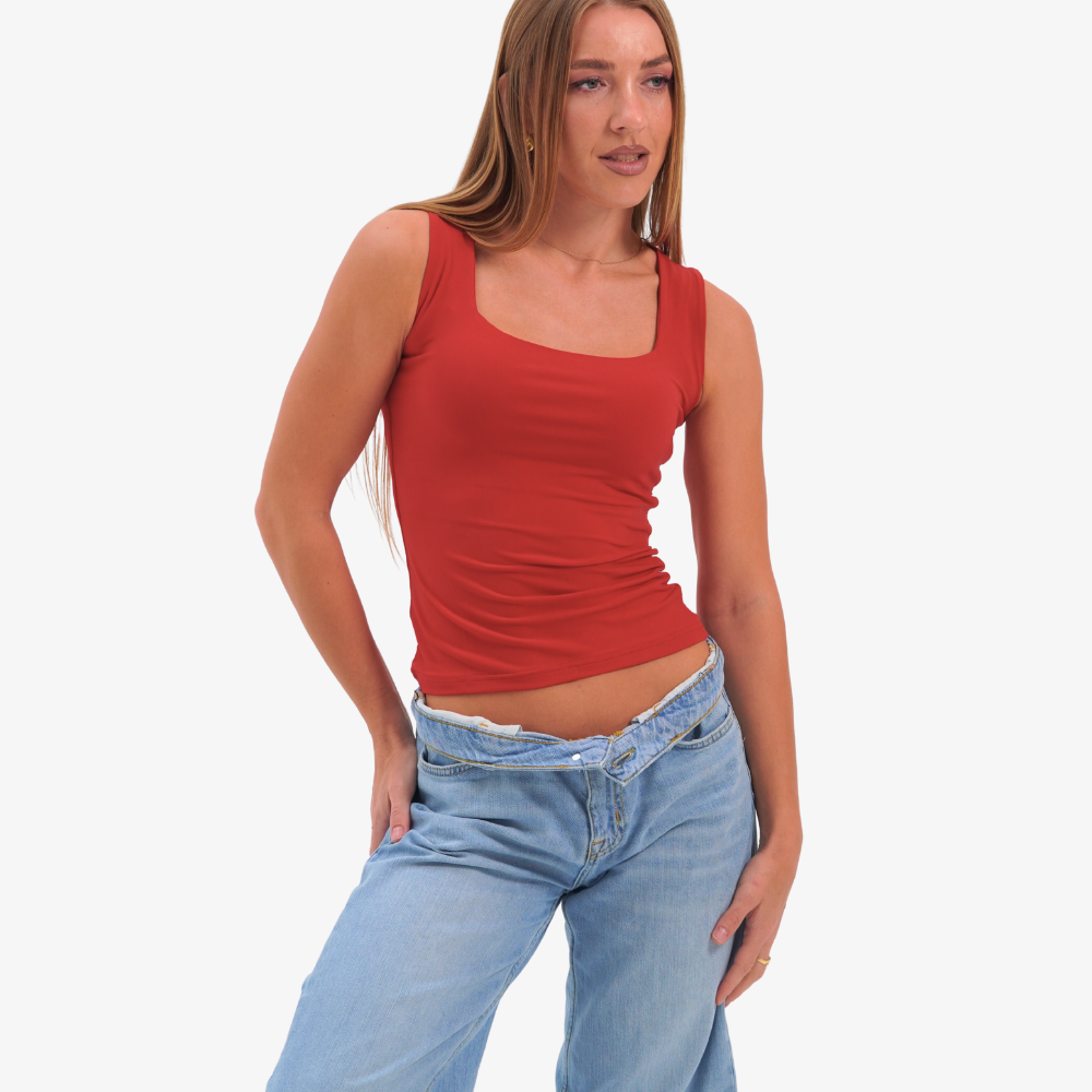 Charlotte top Woman wearing a red tank top and blue jeans on a white background