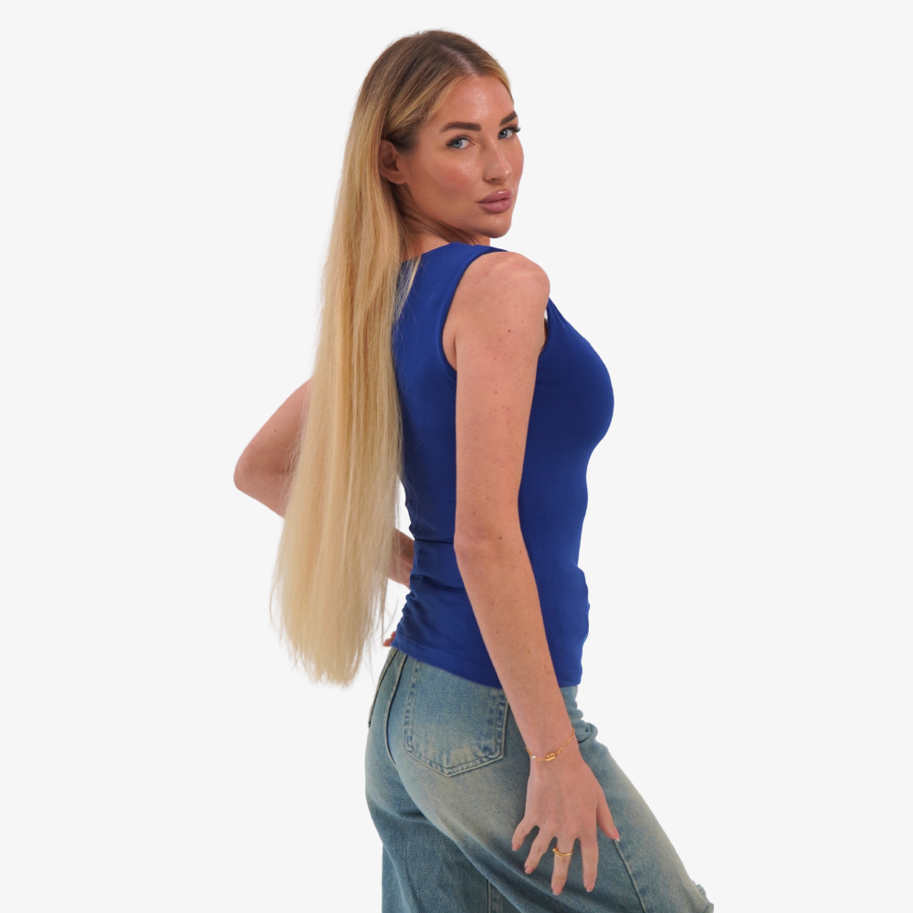 Charlotte top Woman wearing a blue sleeveless top and jeans on a white background