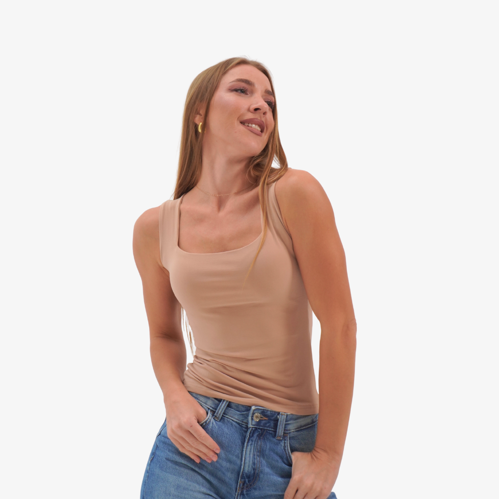 Charlotte top Woman wearing a beige tank top and blue jeans on a white background